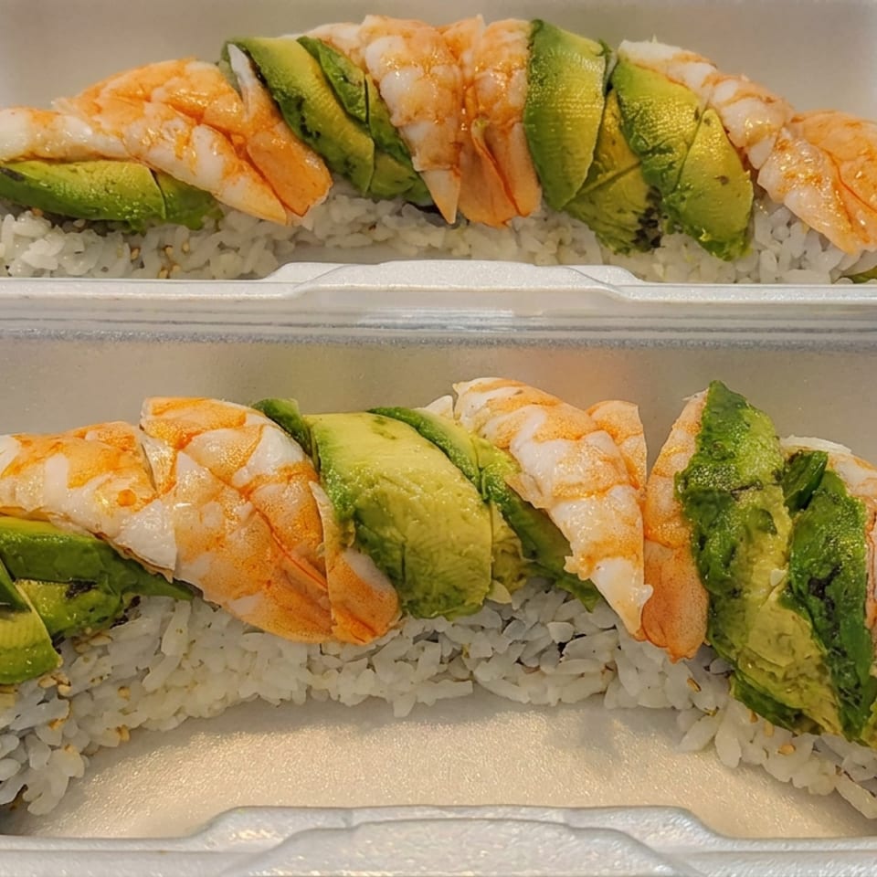 Two takeout containers hold shrimp and avocado sushi rolls over white rice.